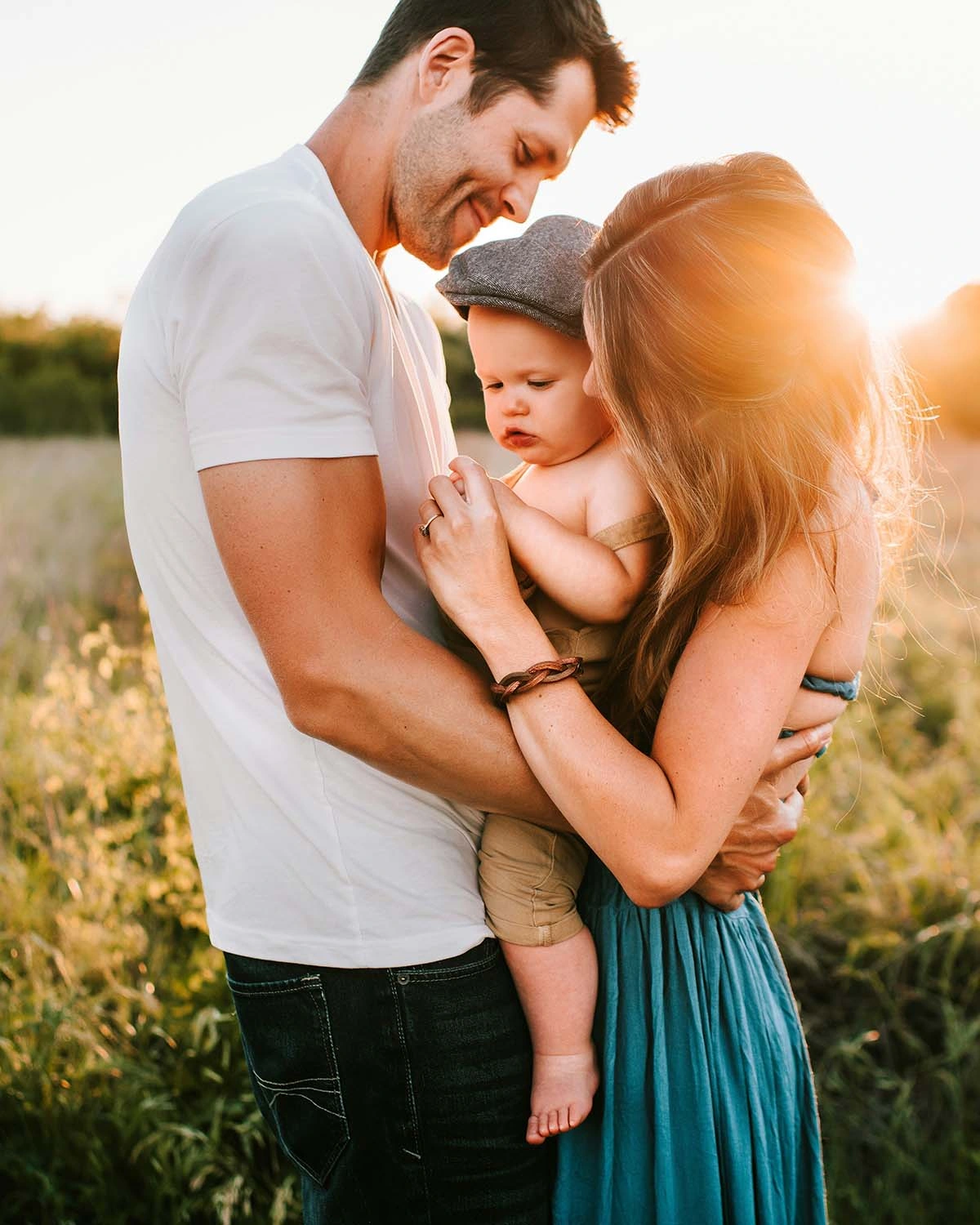 jessica-rockowitz-6c4Uhhe68yQ-unsplash-cropped A family of four smiling together in a sunny field, surrounded by tall grass and wildflowers